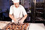 Confectioner positioning chocolate cookies on baking tray