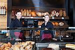 Two female shop assistants at display cabinet in bakery