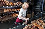 Female shop assistant arranging bread in display cabinet