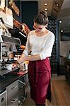 Waitress in coffee shop working at coffee machine