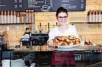 Waitress in coffee shop arranging croissants on counter