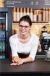 Waitress in coffee shop leaning against counter, portrait