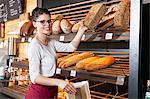 Shop assistant in bakery packing bread into a bag