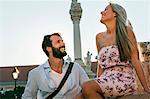 Young couple flirting and laughing by pillar in town