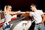 Young couple leaning against propeller airplane