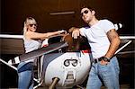 Young couple standing by propeller airplane