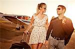 Couple with luggage in front of private airplane