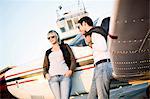 Young couple standing by propeller airplane