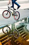 Reflections in a puddle of BMX biker performing a stunt