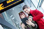 Young couple in airport building using digital tablet