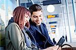 Young couple in airport building using digital tablet