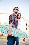 Young couple with skateboard walking in town