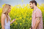 Young couple falling in love in colza field, Tuscany, Italy