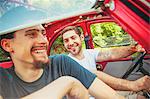 Portrait of two young men in red car smiling merrily