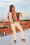 Young woman playing accordion on roof terrace