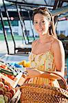 Young woman buying vegetables at market stall