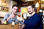 Young men toasting with beer in pub, Dorset, Bournemouth, England