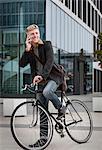 Young businessman with bicycle using phone, Munich, Bavaria, Germany