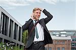 Happy young businessman using phone, Munich, Bavaria, Germany