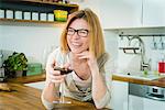 Senior woman in kitchen drinking red wine