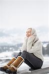 Beautiful woman sitting on ledge of wall and smiling, Crans-Montana, Swiss Alps, Switzerland