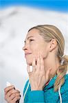 Beautiful woman applying moisturizer on her face, Crans-Montana, Swiss Alps, Switzerland