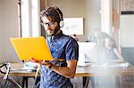 Casual businessman wearing headphones and using laptop in office