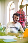 Portrait confident casual businessman using laptop in office