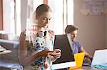 Casual businesswoman with headphones texting on cell phone in office