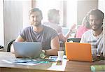 Portrait confident creative businessmen working at laptops in office