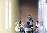 Casual businessman leading meeting at office table