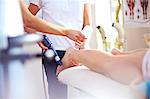 Masseuse applying gel to woman's leg in preparation for ultrasound probe