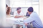 Architects drafting blueprints at laptop in office