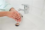 Senior woman washing hands in bathroom sink, Munich, Bavaria, Germany