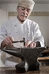 Senior craftsman shaping of copper ring at workshop, Bavaria, Germany