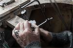 Senior goldsmith shaping crystal with hand saw in workshop, Bavaria, Germany