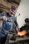 Senior male jeweler melting and casting with blow torch at workshop, Bavaria, Germany