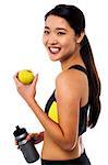 Fitness woman holding sipper bottle and fresh green apple