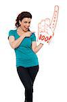 Smiling young woman pointing at large foam hand isolated against white background