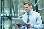 Young businessman reading newspaper at outdoors