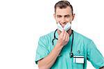 Male doctor removing his surgical mask