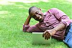 Handsome man using digital tablet while lying on grass