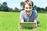 Boy lying on meadow, browsing on his new tablet pc