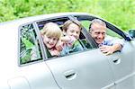 Father with his kids posing from car looking out windows
