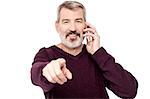 Senior man pointing while talking on mobile phone