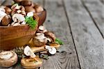 Fresh raw portabello mushrooms with knife in wooden bowls on old wood background