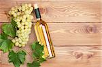 White wine bottle and bunch of white grapes on wooden table background with copy space