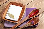 Wood kitchen utensils and spices over wooden table background with notepad for copy space