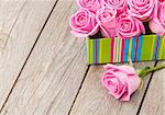 Valentines day background with gift box full of pink roses over wooden table with copy space