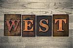 The word "WEST" theme written in vintage, ink stained, wooden letterpress type on a wood grained background.